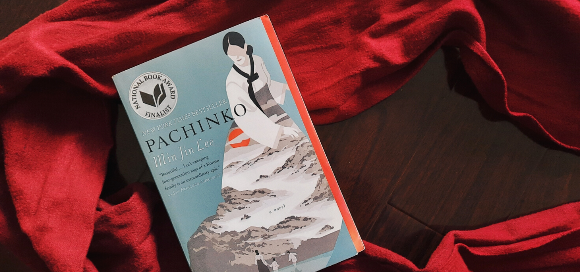 Pachinko by Min Jin Lee sits on top of a red scarf strewn on the ground